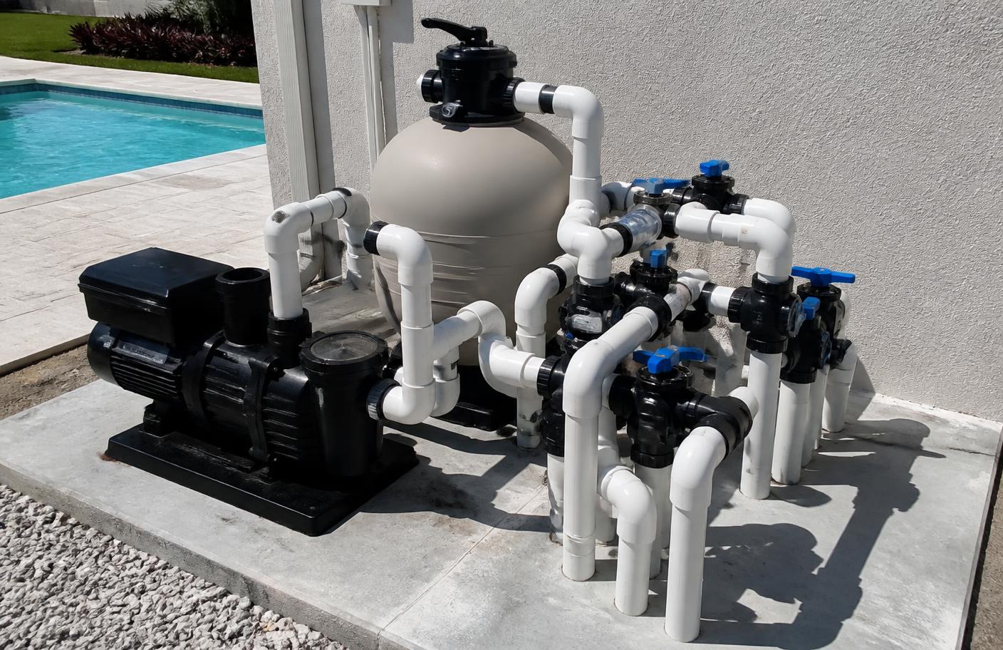 Residential pool pump and filter equipment pad beside a backyard pool